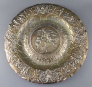 A large embossed white metal charger, decorated with musical trophies, masks and classical figures