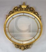 A mid 20th century carved giltwood wall mirror, with urn and scroll surmount, oval marginal plate