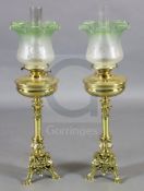 A pair of Victorian brass oil lamps, with green tinted frosted glass shades and foliate scroll