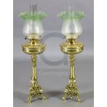 A pair of Victorian brass oil lamps, with green tinted frosted glass shades and foliate scroll