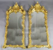 A pair of 19th century French carved giltwood wall mirrors, with scallop and scroll crests flanked