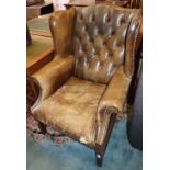 A buttoned green leather wing armchair, W.78cm