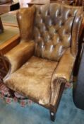 A buttoned green leather wing armchair, W.78cm