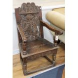 A 17th century carved oak panel-back open armchair, W.62cm