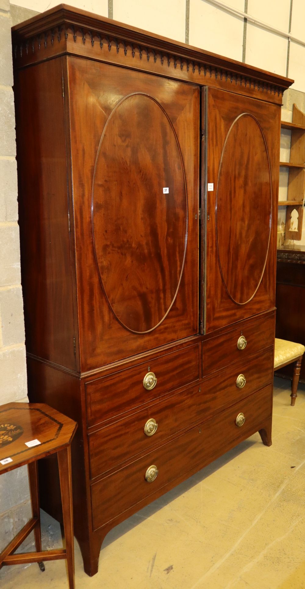 A Regency mahogany linen press, fitted oval panelled doors now enclosing hanging space to the left