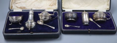 A George V three piece silver condiment set with pair of spoons and a similar three piece set with