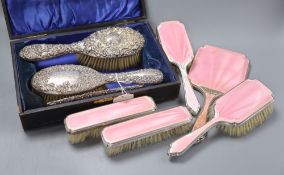 An Edwardian silver backed hair brush and comb set in fitted case, and a five piece pink enamelled