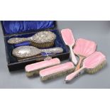 An Edwardian silver backed hair brush and comb set in fitted case, and a five piece pink enamelled