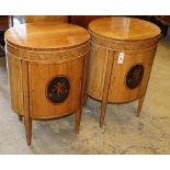 A pair of Edwardian inlaid satinwood bedside cupboards of oval form, decorated with cupid panels,