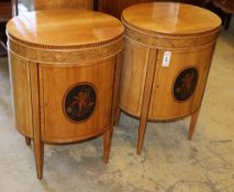 A pair of Edwardian inlaid satinwood bedside cupboards of oval form, decorated with cupid panels,