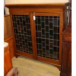 An Edwardian oak bookcase enclosed by stained leaded glass doors, W124cm, D.34cm, H.128cm