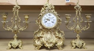 A Louis XV design cast ormolu rococo eight day mantel clock, with matching two branch candelabra, by