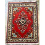 A Qum red ground rug, 100 x 74cm