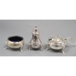 A silver three piece cruet set, with embossed girdle, three paw feet and blue glass liner,