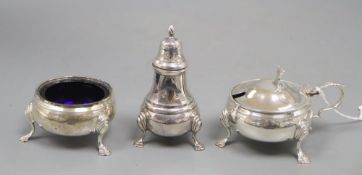 A silver three piece cruet set, with embossed girdle, three paw feet and blue glass liner,