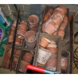 A large quantity of assorted terracotta plant pots, together with a garden trolley and a saw,
