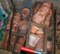 A large quantity of assorted terracotta plant pots, together with a garden trolley and a saw,