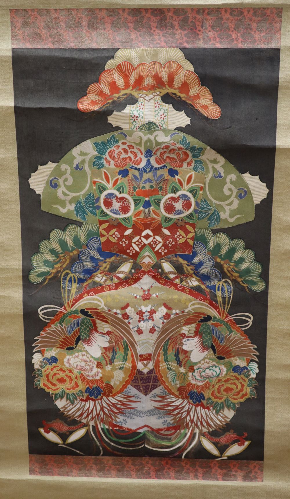 A Japanese scroll decorated with a design of bright multi-coloured motifs creating a central