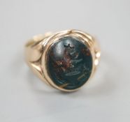 A 9ct and carved crested oval bloodstone set signet ring (stone a.f.), size K, gross 4.5 grams.