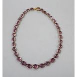 A Victorian pinchbeck and graduated amethyst coloured paste set necklace, 45.2cm, lacking central