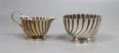 A silver wrythen embossed sugar bowl, Birmingham 1905 and a pear shaped milk jug, with broken scroll