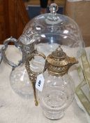 A glass cake stand, a silver plated claret jug and a brass mounted claret jug