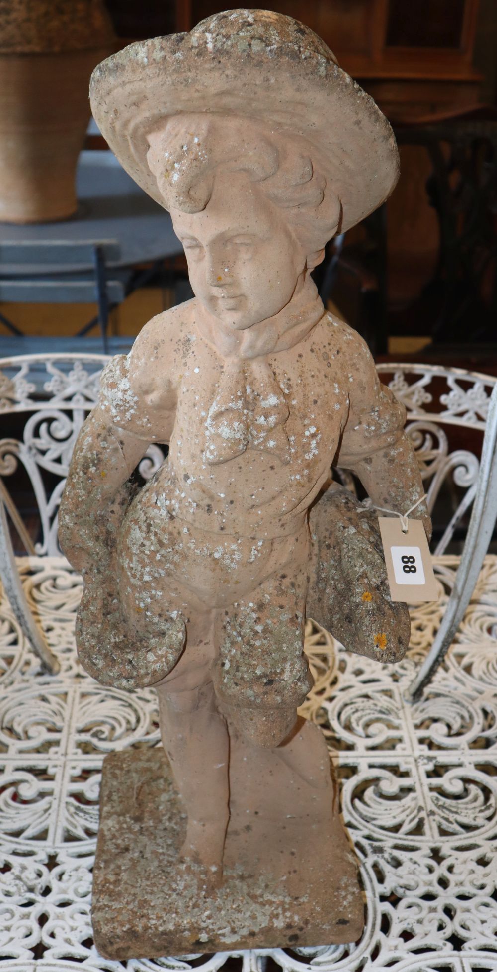 A terracotta garden ornament, boy with a scythe, H.70cm