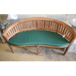 A teak garden banana bench with cushion seat, W.160cm, D.54cm, H.85cm