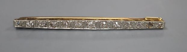 An early 20th century 15ct, plat and graduated thirteen stone diamond set bar brooch, 57mm, gross