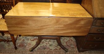 A Regency faded mahogany drop leaf breakfast table, on downswept legs with brass caps and castors,
