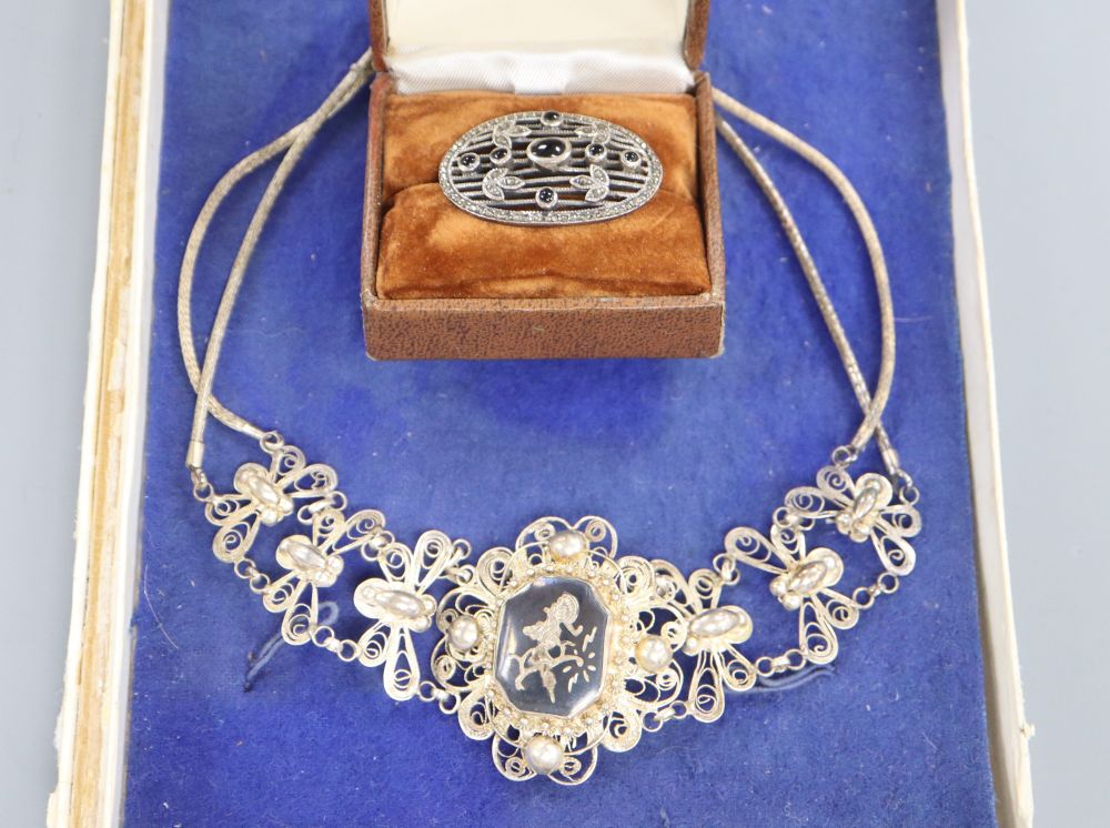 A Siamese filigree white metal and niello necklace and a marcasite brooch.