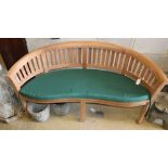 A teak garden banana bench with cushion seat, W.160cm, D.54cm, H.85cm