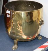 A brass log bin with paw feet and lion handles