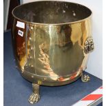 A brass log bin with paw feet and lion handles