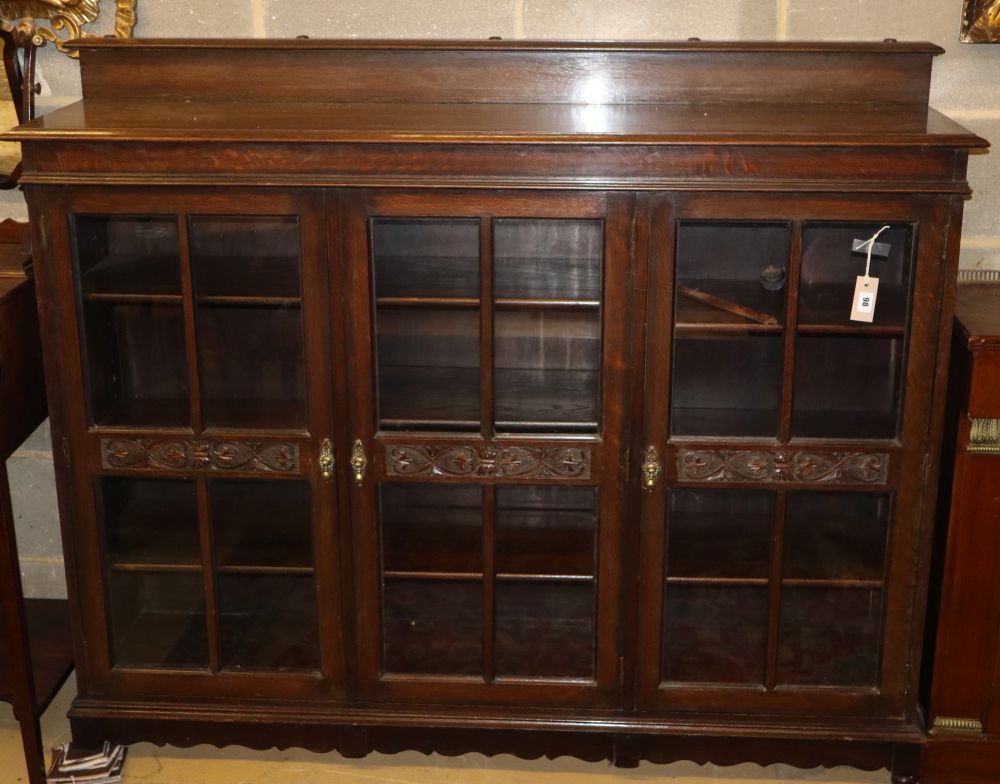 A 1920's carved oak three door bookcase, W.152cm, D.36cm, H.120cm