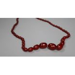 A single strand graduated oval simulated cherry amber necklace, 72cm, gross 64 grams.