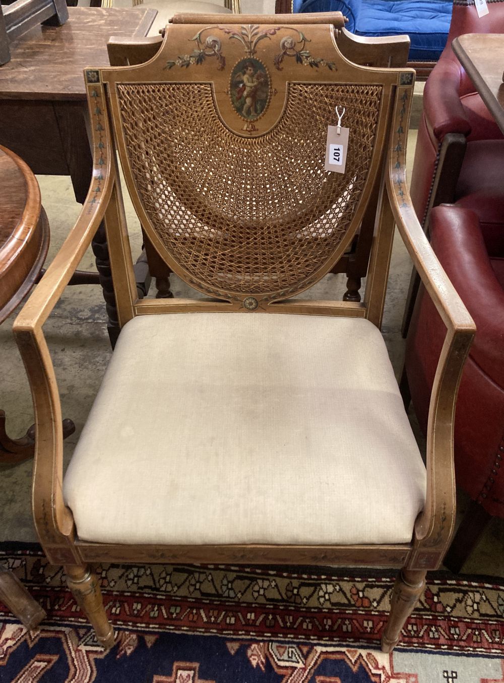 A pair of Edwardian Sheraton revival painted satinwood caned back elbow chairs, width 53cm, height