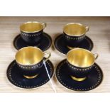 A set of four miniature Royal Worcester cups and saucers, in black and gilt design