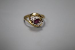 A modern 18ct gold, single stone ruby and four stone diamond set crossover ring, size L, gross 3.5