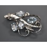 A white metal and four stone aquamarine set scroll brooch, 32mm, gross 4.1 grams.