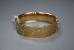 A modern engraved 9ct gold hinged bangle, gross 26.8 grams.