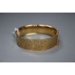 A modern engraved 9ct gold hinged bangle, gross 26.8 grams.