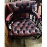 A reproduction tub shaped swivel desk chair upholstered in buttoned burgundy leather