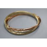 A 9ct three-colour gold bangle of oval, hollow, hinged design with overlapping bands, 18.1g