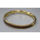 A gilt white metal and twin row red stone set hinged bracelet, with safety chain, gross 22.1 grams.