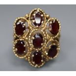 A 14k yellow metal and seven stone garnet set cluster dress ring, size L, gross 11.1 grams.