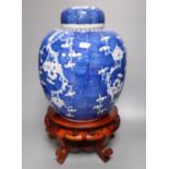 A pair of large Chinese blue and white 'prunus' jars and covers, early 20th century, wood stands,