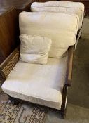 A pair of early 20th century mahogany framed bergere armchairs with caned sides, and cream brocade