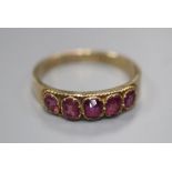 An early 20th century 10ct yellow metal and graduated five stone garnet set half hoop ring, size