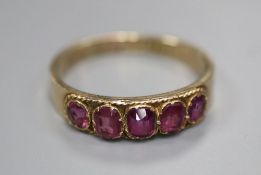 An early 20th century 10ct yellow metal and graduated five stone garnet set half hoop ring, size